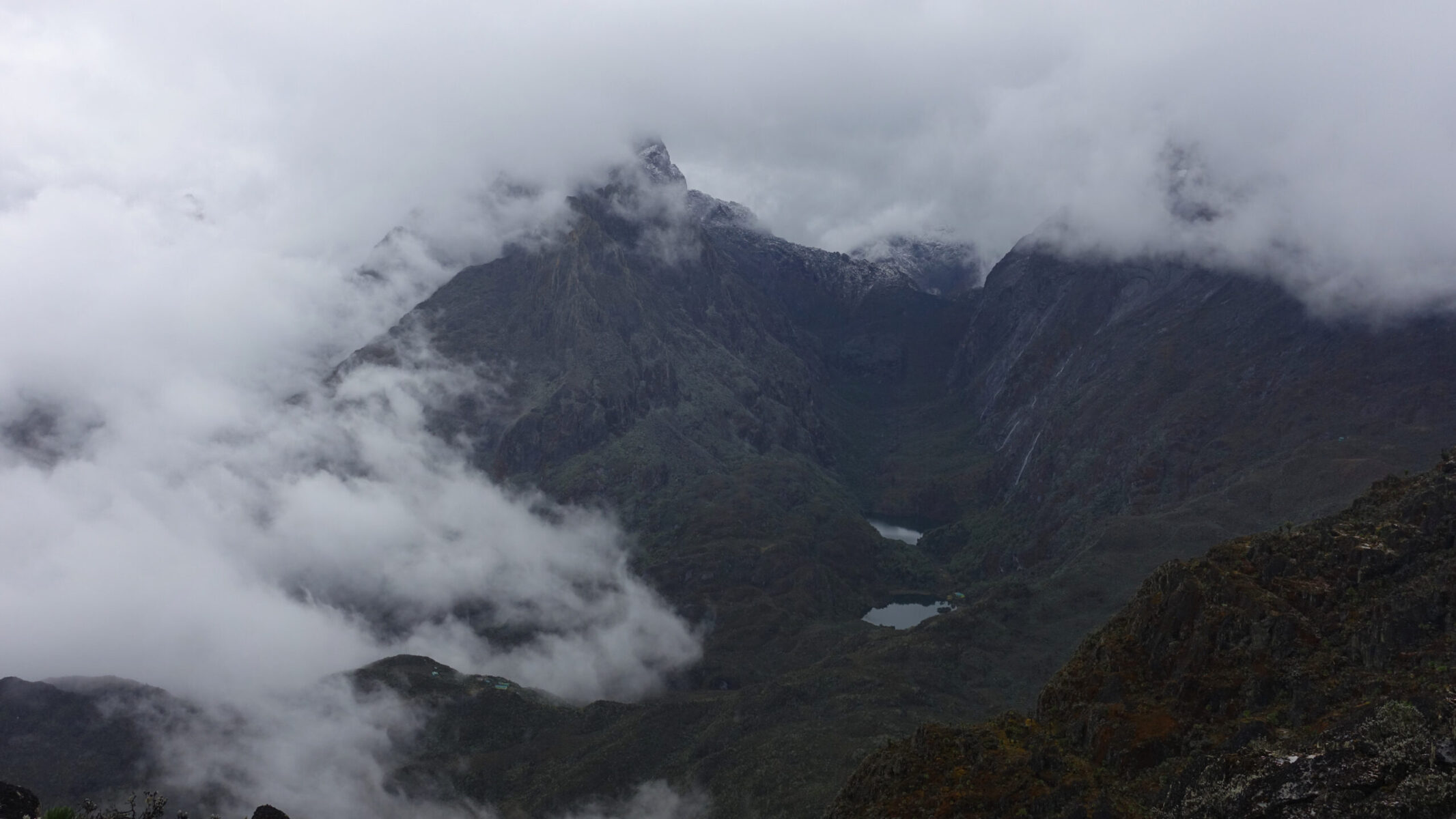 Looking back where I started the day during a cloud break. Central is Scott-Elliott Pass, flanked by Stanley (L) and Baker (R), and both Hunwick's Camp (RTS) and Kitandara Hut (RMS) in the valley. Mount Stanley and Mount Baker in the cloud